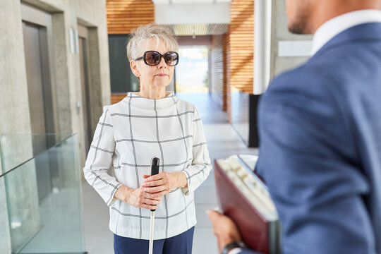 Blinde alte Frau mit Blindenstock im Business Büro