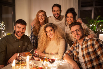 holidays, celebration and people concept - happy friends taking selfie at home christmas dinner party
