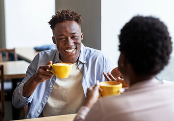 Fototapeta na wymiar Handsome black guy with his girlfriend drinking coffee together at city cafe