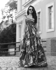 Pretty lady in green colorful dress. Summer outdoor full length portrait. Beautiful woman with long wavy hair wearing sunglasses