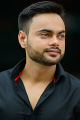Fototapeta premium Young handsome bearded Indian businessman in the city