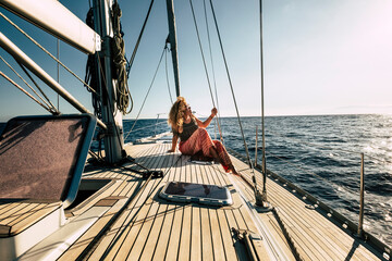 Beautiful young woman enjoy summer holiday vacation or excursion on sailboat with sun and ocean...
