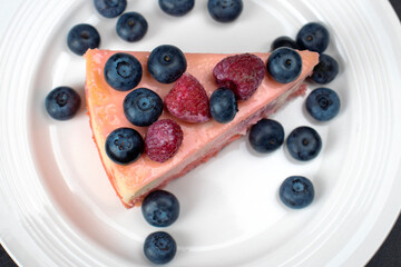 Cheesecake with berries on a white plate top view. Flat lay food photography.
