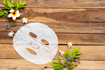 natural aroma sheet mask extract herbal essence face mask health care for skin face with flowers arrangement flat lay style on background wooden