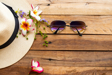 sunglasses and hat of lifestyle woman relax summer with purple flowers ,frangipani  arrangement flat lay style on background wooden