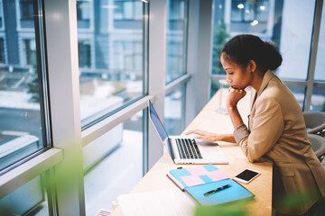 Young afro american female IT developer brainstorming while finding solution in coding program for...