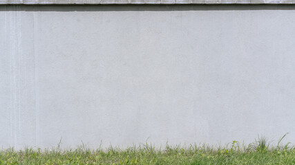 large gray empty concrete building wall with blank place for advertising mock-up under green grass