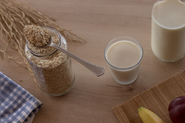 Mesa de madera con el desayuno con un bote de avena leche y fruta vista desde arriba