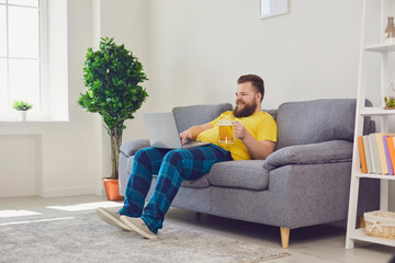 Online communication. Funny guy with beer chatting to friends on laptop from home. Bearded man making video call