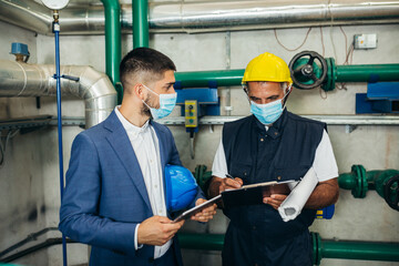 industry worker and his manager discussing in plant. safety face mask due covid virus