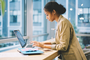 Concentrated female administrative typing messages to employee coordinating work being in business...