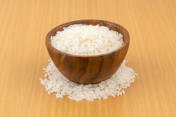 Jusmine rice in wooden bowl on wooden table.