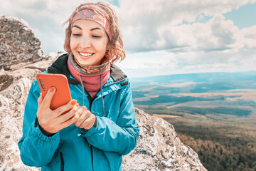 Asian woman on top of a mountain connects to a GPS Navigator and an app on her phone to chat with...