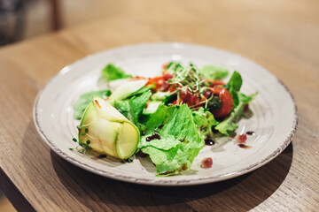 Haute cuisine salads with green vegetables and herbs and avocado slices on the table in the restaurant