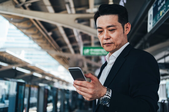 Business man with smartphone, waiting at the train station platform stock photo