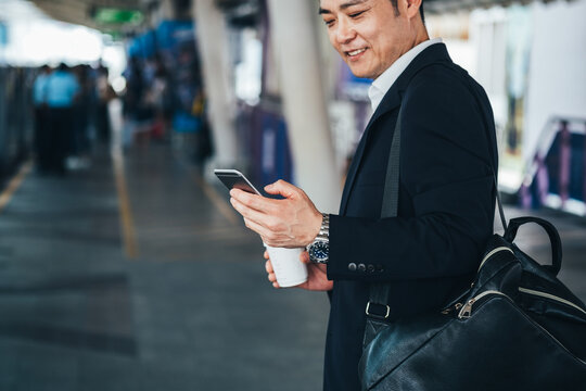 Business man looking phone at train station stock photo