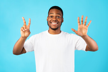Black Man Showing Number Seven Smiling To Camera, Blue Background