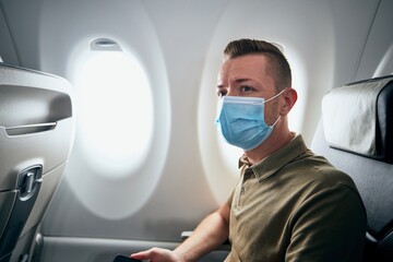 Fototapeta na wymiar Man wearing face mask inside airplane