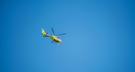 Yellow ambulance helicopter against blue sky during summertime. Rescue and medical support.