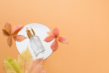 Glass cosmetic bottle with essential oil on autum,n background