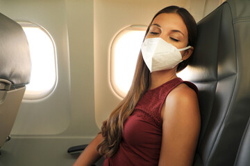 Brazilian woman with protective face mask sleeping relaxed on airplane flight during pandemic...