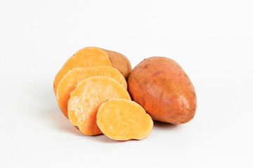 Farm raised organic sweet potato tubers laid in composition on textured background. The edible tuberous root vegetable on table counter. Clean eating concept. Background, close up, flat lay, top view.