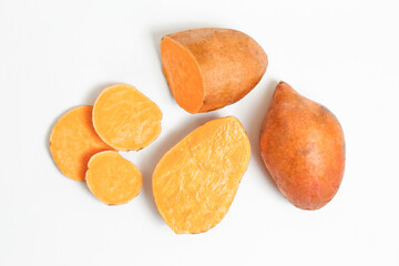 Farm raised organic sweet potato tubers laid in composition on textured background. The edible tuberous root vegetable on table counter. Clean eating concept. Background, close up, flat lay, top view.