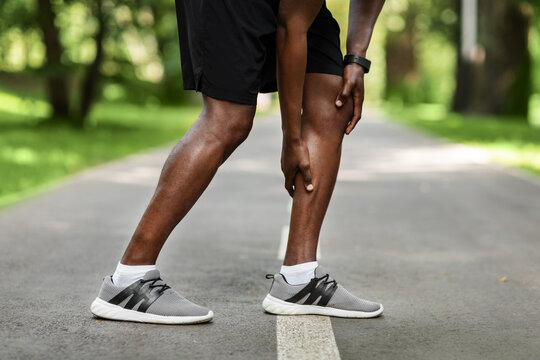 African sportsman massaging leg, feeling pain after running