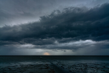 Landscape view of sea at tide and silhouette dark dramatic sunset sky and clouds in the evening. Sunset sky of tropical beach. Beauty in nature. Dark background for sad, death, and depression.