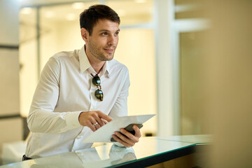 Businessman checking in at the hotel and filling paperwork at reception desk.