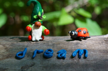 The inscription dream on the wooden surface. Next to the figure of a dwarf and a ladybug.
