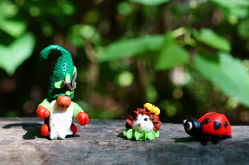 Figure of a dwarf in a wooded area. Next to the figure of a hedgehog and a ladybug.