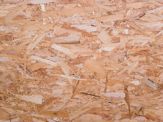 Background image. The textured surface of a wooden OSB board in natural light.
