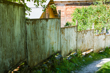 Old village house fence, road and plants