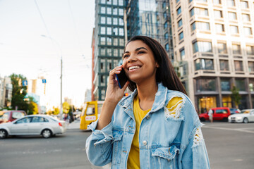 Cheerful young woman making a phone call outdoors