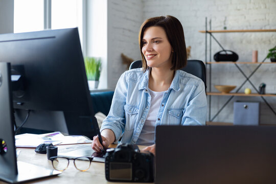 Portrait of graphic designer working in office with laptop,monitor,graphic drawing tablet and color palette.Retouching images in special program.Retoucher workplace in photo studio.Creative agency.