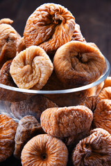 Composition with bowl of dried figs on wooden table