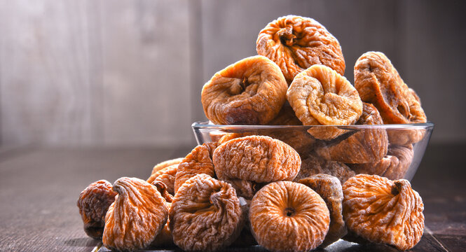 Composition with bowl of dried figs on wooden table
