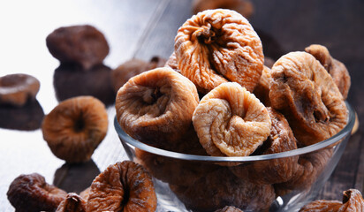 Composition with bowl of dried figs on wooden table