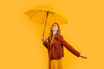 Happy cheerful girl in a yellow dress and autumn jacket, laughing and having fun with a yellow...