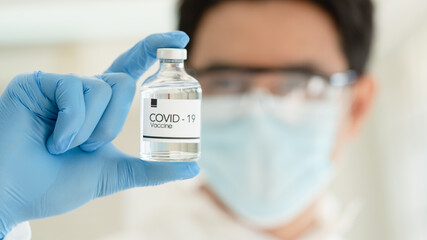 scientist in laboratory with bottle of covid-19 vaccine 