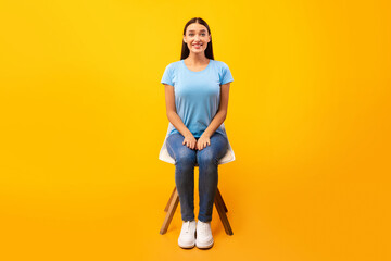 Studio shot of young woman sitting on the chair