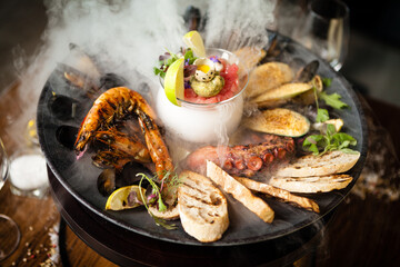 Seafood platter for 2-4 persons. Octopus, blue mussels, cooked green mussels, grilled tiger prawns, tuna tartare. Delicious seafood closeup served on a table for lunch in modern gourmet restaurant