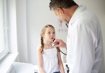 Doctor in white coat examines young, pretty girl in his practice or in a hospital