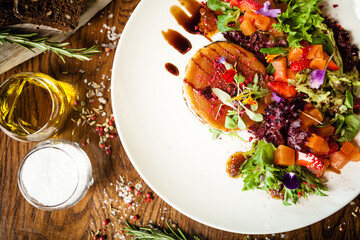 Goat cheese salad. Strawberry-melon salad with chilli, apple-orange sauce, fig jam on white plate. Delicious meat food closeup served on a table for lunch in modern cuisine gourmet restaurant