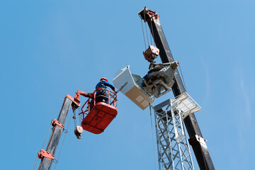 Workers on the aerial platform with the help of a crane carry out the installation of the wind...