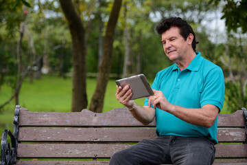 Obraz premium Portrait of mature handsome man relaxing at the park
