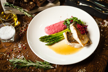 Pike-perch fillet. Asparagus, pearl couscous, white wine sauce, beet-flavored mashed potatoes. Delicious seafood fish closeup served on a table for lunch in modern cuisine gourmet restaurant