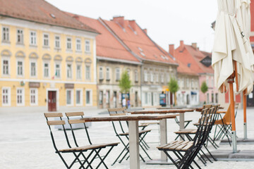 Empty wooden table with chairs in front of cafe in old city center.
