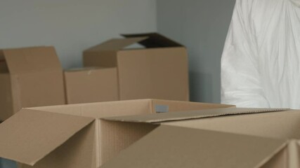 A man in a protective suit and gloves packs food in boxes